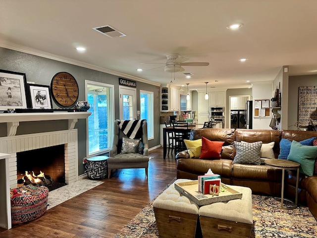 living room featuring ornamental molding, dark hardwood / wood-style floors, ceiling fan, and a fireplace