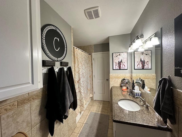 bathroom with tile walls, tile patterned flooring, vanity, a textured ceiling, and a shower with curtain