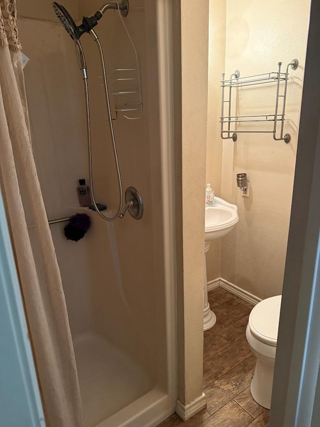 full bath featuring toilet, baseboards, and a stall shower