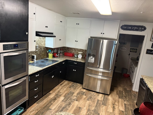 kitchen featuring under cabinet range hood, wood finished floors, appliances with stainless steel finishes, and white cabinets