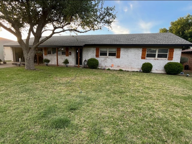 ranch-style house featuring a shingled roof and a front lawn