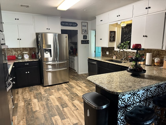 kitchen featuring dishwashing machine, wood finished floors, visible vents, a sink, and stainless steel refrigerator with ice dispenser