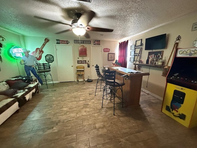 bar with visible vents, a bar, a ceiling fan, and a textured ceiling