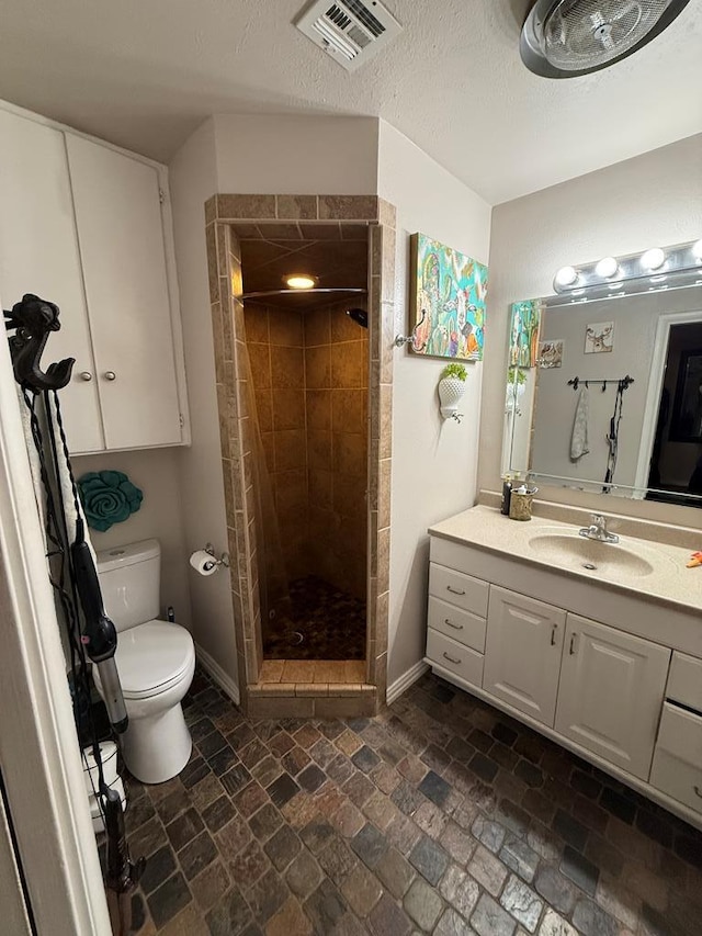 bathroom featuring visible vents, toilet, a shower stall, baseboards, and vanity