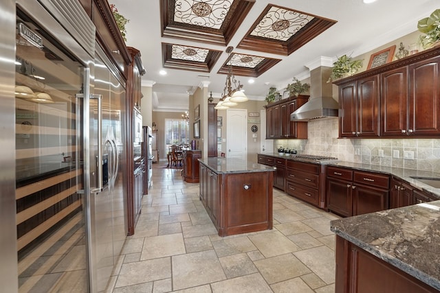 kitchen featuring tasteful backsplash, wall chimney exhaust hood, crown molding, pendant lighting, and a center island