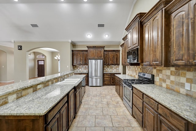 kitchen with arched walkways, visible vents, stainless steel appliances, and a sink