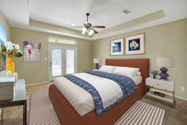 bedroom featuring visible vents, a raised ceiling, baseboards, and access to outside