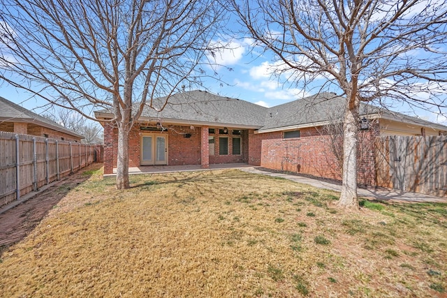 back of house featuring a patio, a fenced backyard, brick siding, and a lawn