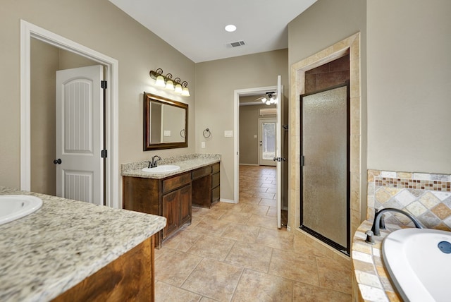 full bath with visible vents, a garden tub, two vanities, a stall shower, and a sink