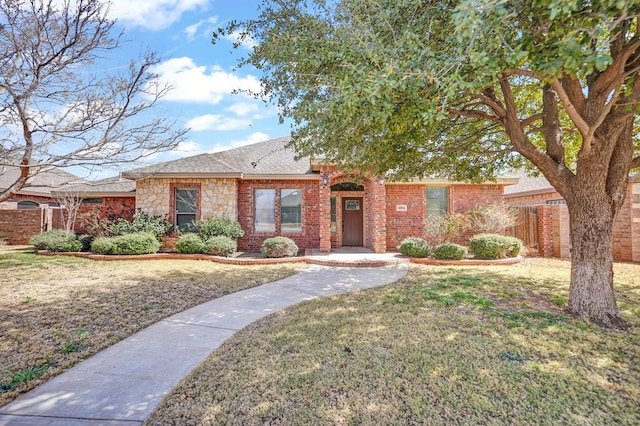 single story home with brick siding, roof with shingles, a front yard, and fence