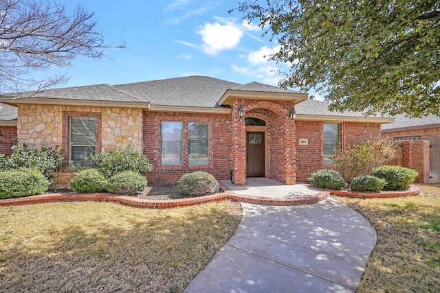 ranch-style house with a front lawn, fence, brick siding, and a shingled roof