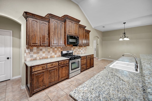 kitchen featuring arched walkways, a sink, decorative backsplash, black microwave, and stainless steel gas stove