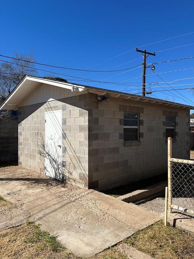 view of side of property featuring fence and concrete block siding