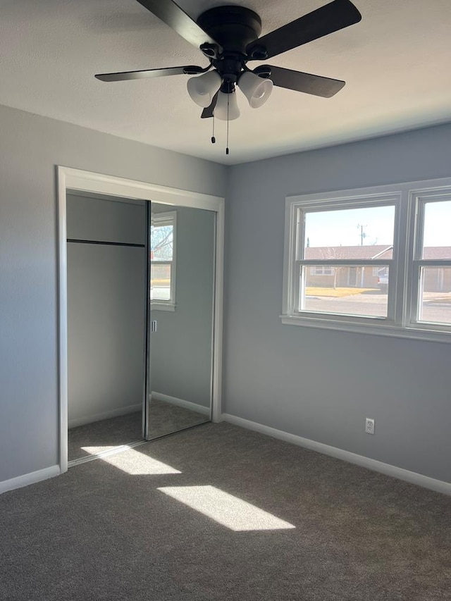 unfurnished bedroom with a closet, carpet, a ceiling fan, and baseboards