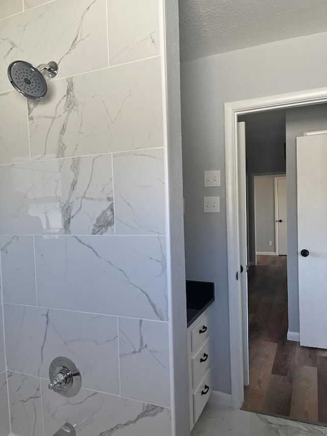 bathroom with vanity, a textured ceiling, and tiled shower / bath