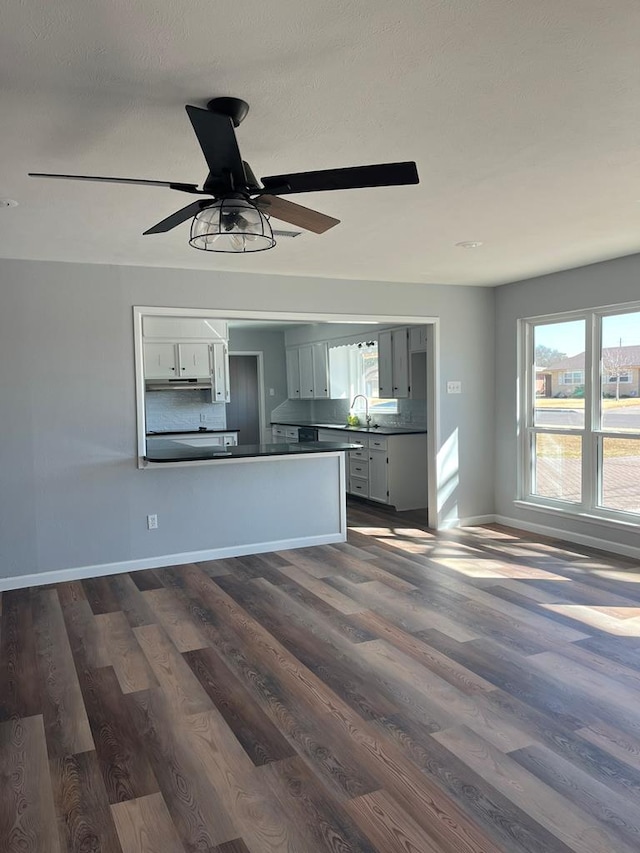 unfurnished living room with sink, dark wood-type flooring, and ceiling fan