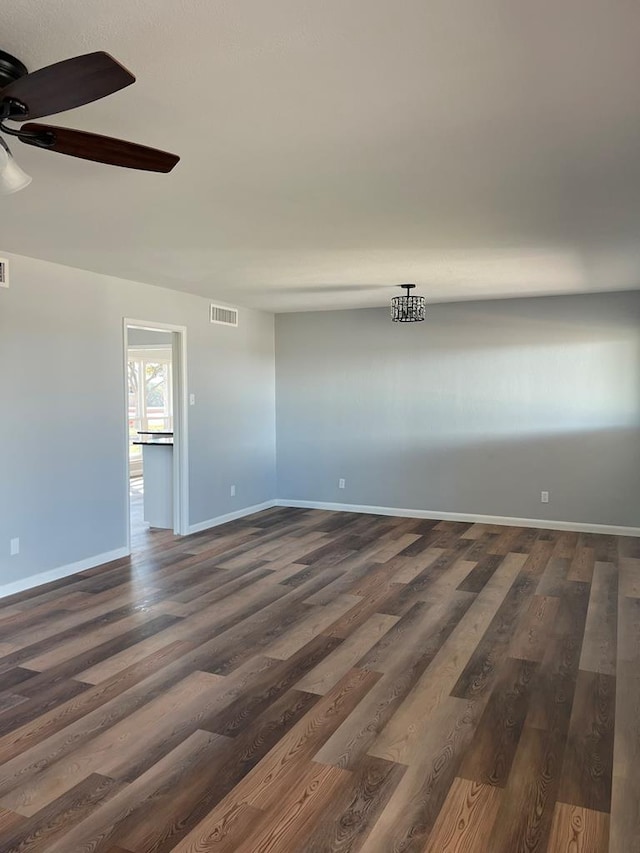 unfurnished room with dark wood-style floors, ceiling fan, visible vents, and baseboards