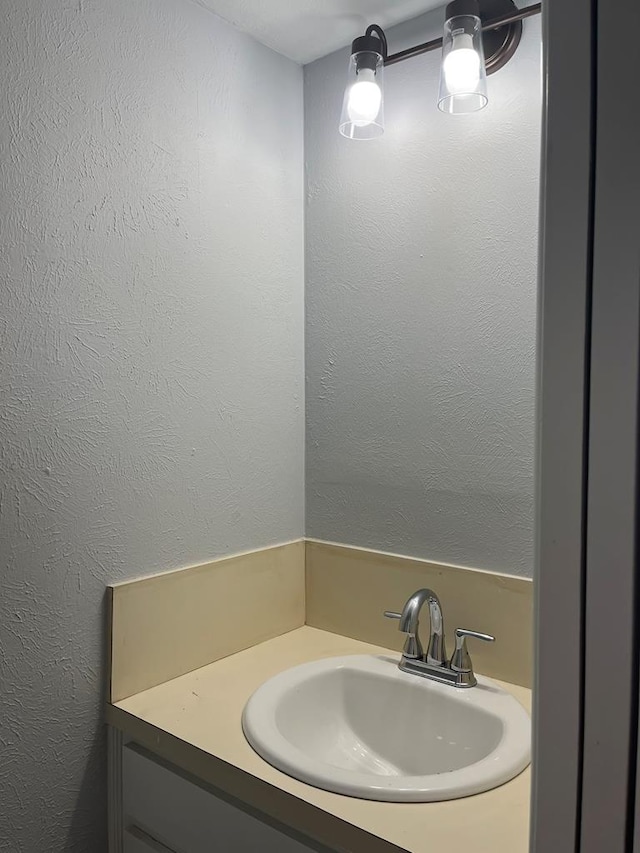 bathroom with a textured wall and vanity