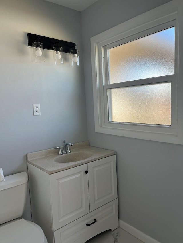 half bath featuring vanity, toilet, and baseboards