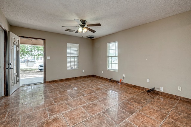 3608 S County Rd 1195, Midland, TX 79706 - empty room featuring plenty of natural light, a ceiling fan, a textured ceiling, and baseboards