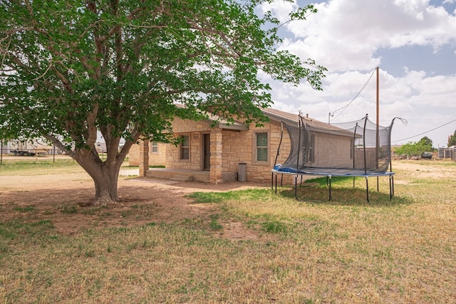 3608 S County Rd 1195, Midland, TX 79706 - back of house with a trampoline, a yard, and stone siding