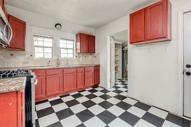 3608 S County Rd 1195, Midland, TX 79706 - kitchen featuring light floors, appliances with stainless steel finishes, a sink, backsplash, and reddish brown cabinets
