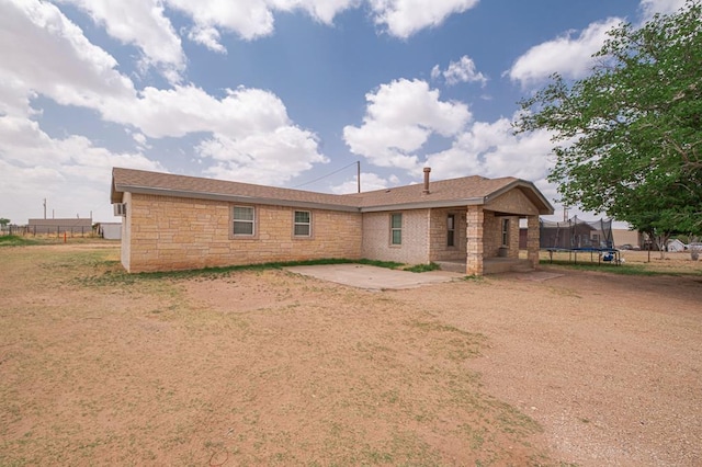 3608 S County Rd 1195, Midland, TX 79706 - back of property featuring a trampoline, a patio, stone siding, and fence