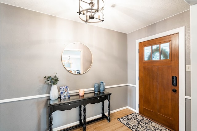 foyer with an inviting chandelier, baseboards, and wood finished floors