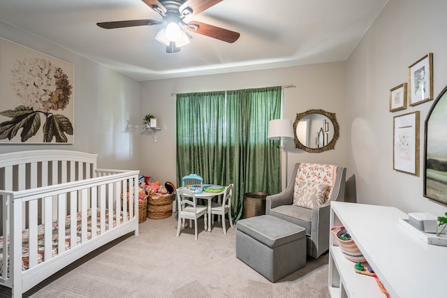 bedroom featuring a crib, ceiling fan, and carpet flooring