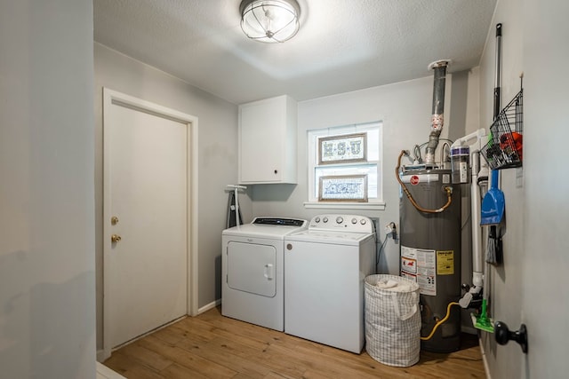 washroom with gas water heater, a textured ceiling, cabinet space, light wood finished floors, and washer and dryer