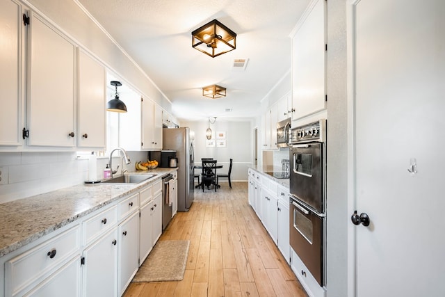 kitchen with visible vents, a sink, white cabinetry, and stainless steel appliances
