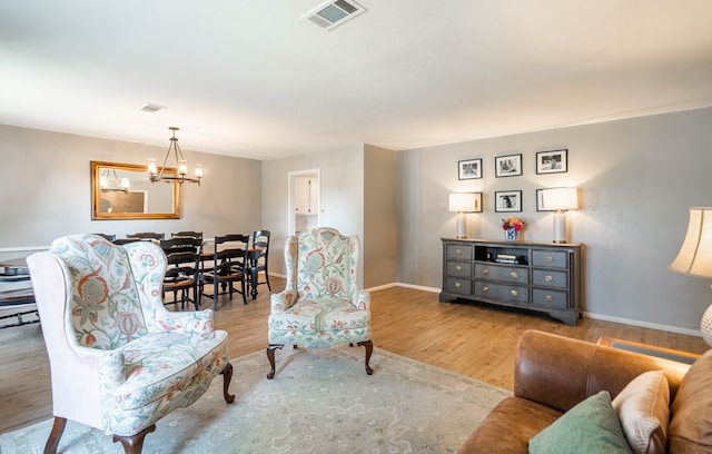 living room with a chandelier, baseboards, visible vents, and wood finished floors