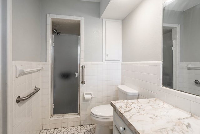 bathroom with wainscoting, vanity, toilet, tile walls, and a shower stall
