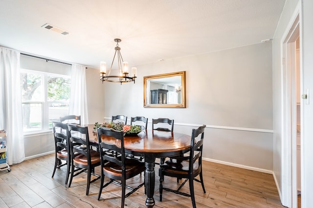 dining space with baseboards, a notable chandelier, light wood-style flooring, and visible vents