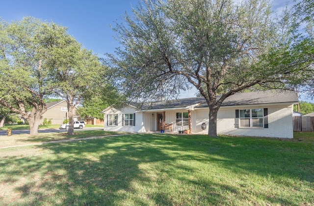 single story home with brick siding, fence, covered porch, and a front yard