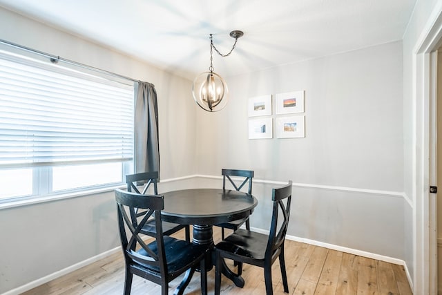 dining room featuring baseboards, a notable chandelier, and light wood-style flooring