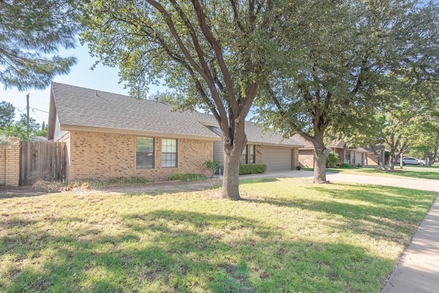 ranch-style home featuring brick siding, fence, concrete driveway, roof with shingles, and a front lawn