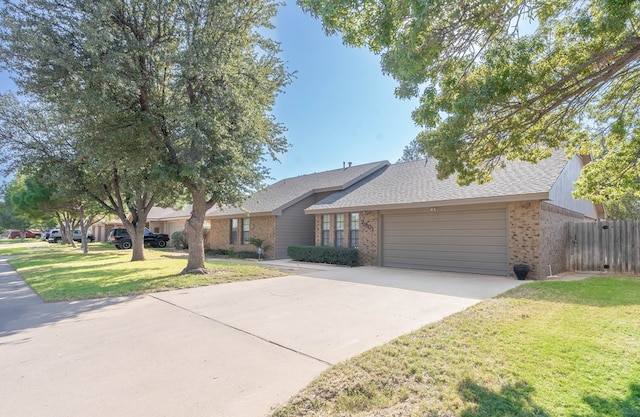 view of front facade with a front yard, concrete driveway, brick siding, and an attached garage