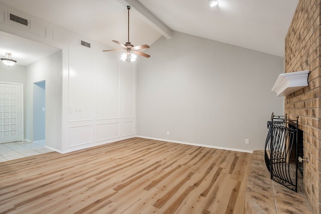 unfurnished living room with light wood-style floors, vaulted ceiling with beams, visible vents, and a fireplace