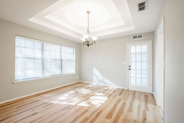 unfurnished room with a raised ceiling, visible vents, and light wood-style flooring