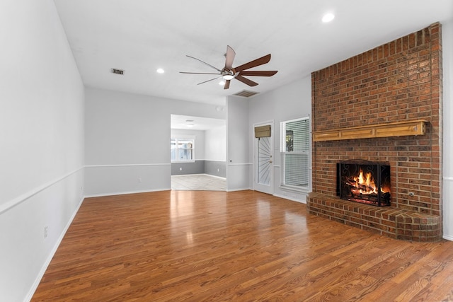 unfurnished living room featuring a fireplace, hardwood / wood-style flooring, a wealth of natural light, and ceiling fan