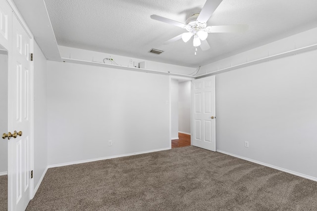 unfurnished room featuring a textured ceiling, dark carpet, and ceiling fan