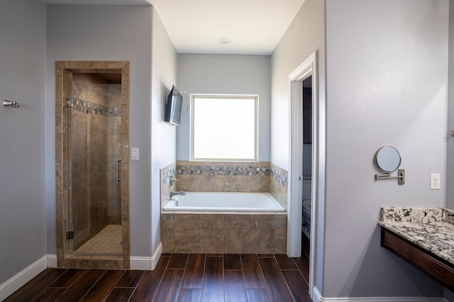 full bathroom featuring a stall shower, toilet, vanity, wood finish floors, and a bath