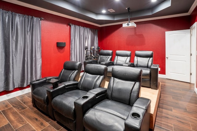 cinema room featuring a tray ceiling, wood finished floors, visible vents, and baseboards