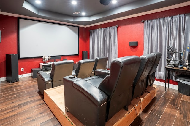 cinema featuring wood finish floors, a raised ceiling, visible vents, and baseboards