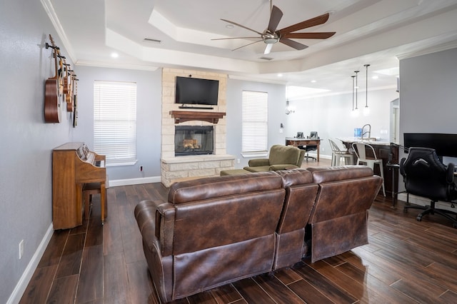 living room featuring dark wood-style floors, a fireplace, baseboards, and a raised ceiling