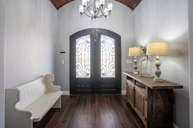 foyer entrance featuring arched walkways, french doors, dark wood-style flooring, lofted ceiling, and baseboards