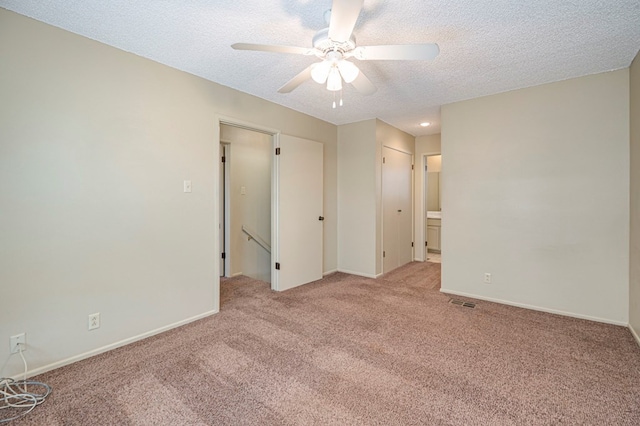 spare room featuring light carpet, ceiling fan, and a textured ceiling