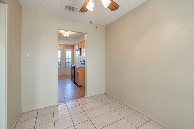 empty room with ceiling fan, light hardwood / wood-style flooring, and a textured ceiling