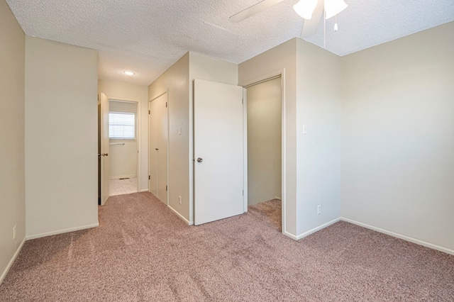 unfurnished bedroom with ceiling fan, a closet, light colored carpet, and a textured ceiling